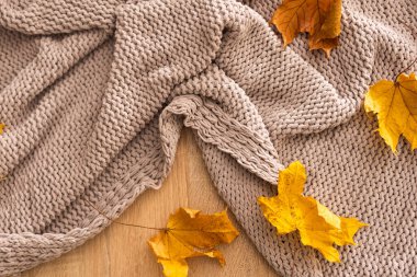 Sonbahar kompozisyonu. Sıcak örülmüş ekose, beyaz yün arka planda sarı yapraklar. Sonbahar, sonbahar konsepti. Düz konum, üst görünüm, kopyalama alanı
