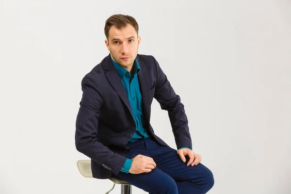 白い背景に分離された青い椅子に座って若い陽気な男の垂直ショット — ストック写真