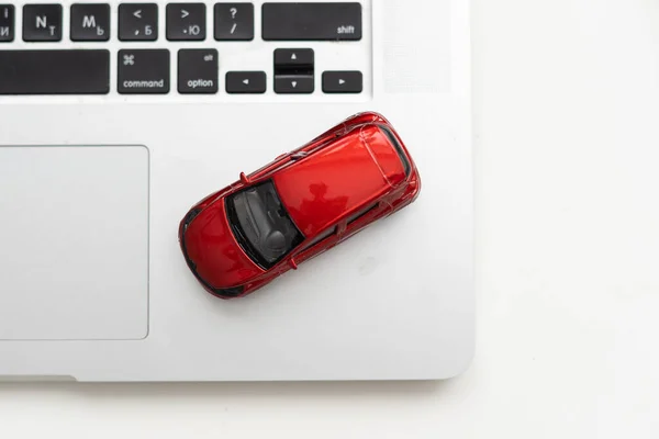 Car model on notebook and mouse on wooden desk. About car business concept such as transportation, rental, sell and buy. High quality photo