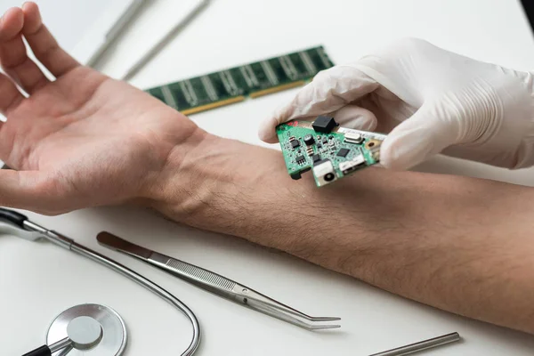 Stock image The cosmetic surgeon made a small incision to insert the chip into the patients arm. Biotechnology, electronic documents and technological future concept. Bionic chip. Biohacking. High quality photo