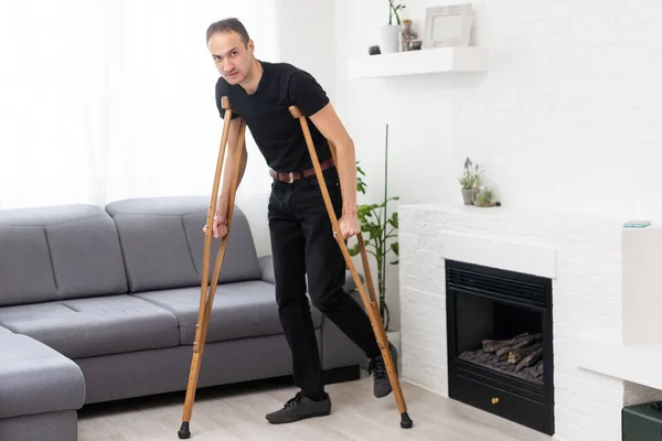 Young leg injured man with crutches.