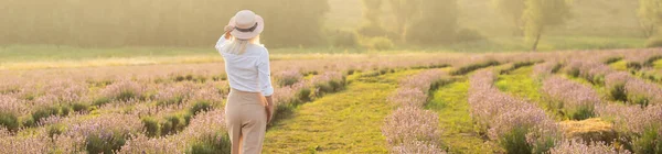 美しい若い健康な女性白いドレスは 夕日の光の下でわら帽子を保持ラベンダー畑を楽しく実行しています — ストック写真