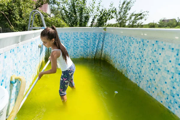 a little girl cleans a very dirty pool.