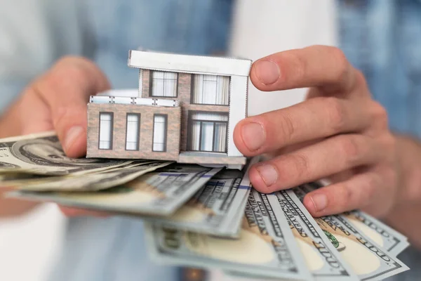 Business people hold banknotes with gray roof houses in banknotes Real estate investment ideas, mortgages, saving money for new homes, home loans with space for entering text. High quality photo