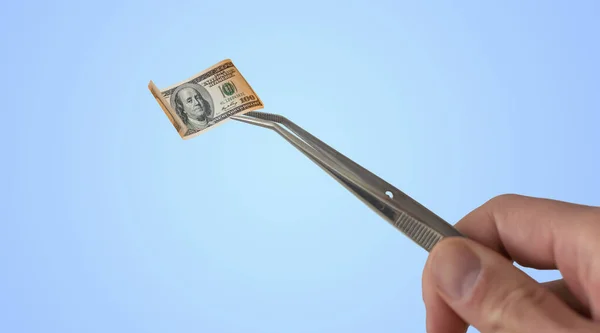 Lab, forensic scientist or medical professional with tweezers takes out rolled-up money. Hands in white gloves hold a test tube with a hundred dollar bill