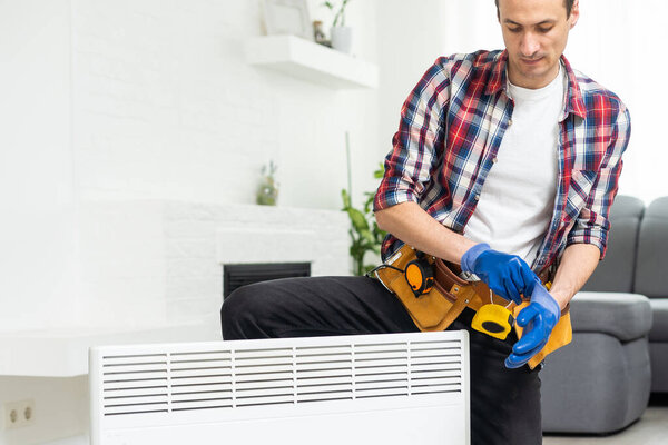 Quality help. Handyman using pipe wrench while repairing radiator battery in the room. Heating restoration. High quality photo