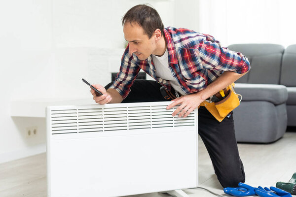 Quality help. Handyman using pipe wrench while repairing radiator battery in the room. Heating restoration. High quality photo