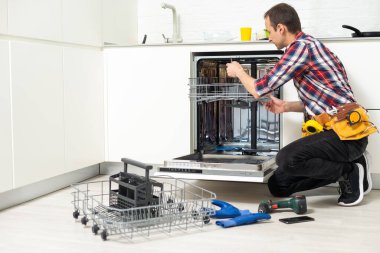 Mutfakta bulaşık makinesini tornavidayla tamir eden bir tamirci. Yüksek kalite fotoğraf