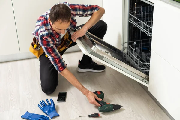 若い男性技術者は台所で食器洗い機を修復します 高品質の写真 — ストック写真