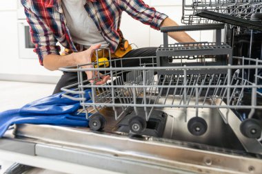Yıkanmış bir bulaşık makinesinin arka planına karşı bir adamın ellerinde bulaşık makinesi için yeni bir pompa. Yüksek kalite fotoğraf