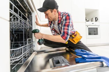 İşçi, bulaşık makinesini tamir etmek için tornavida kullanıyor. Yüksek kalite fotoğraf