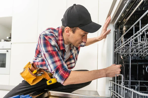 現代のキッチンで食器洗い機を修理サービスマン メンテナンスと家庭支援の概念 高品質の写真 — ストック写真