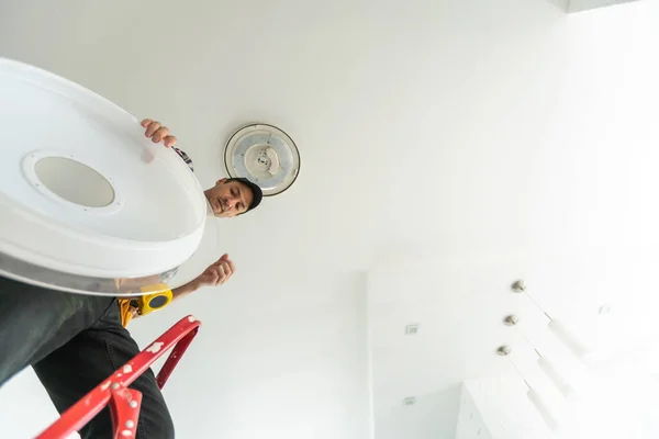 stock image Installing a spotlight in the room. A man is using an insulating tape to the bare electric wires. High quality photo