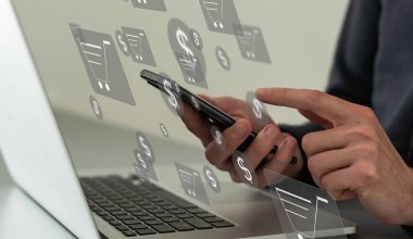 Çevrimiçi alışveriş ve e-ticaret kavramı. Genç adam alışveriş arabası simgesi olan dizüstü bilgisayarı kullanıyor, çevrimiçi mağazada sipariş veriyor, internetten alışveriş yapıyor, klavyede el yazısı olan sanal ekranda konsept kullanıyor.