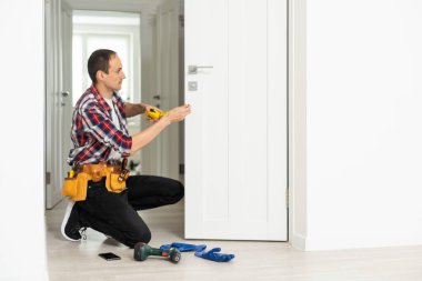 High Angle View Of Male Carpenter With Screwdriver Fixing Door Lock. High quality photo clipart