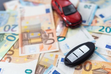 Paranın arka planında oyuncak bir araba ve araba anahtarları..