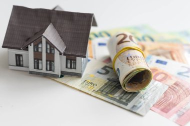 Bir sürü banknotu ve anahtarı olan küçük bir ev modeli. Emlak sigortası. Yatırım. Yüksek kalite fotoğraf
