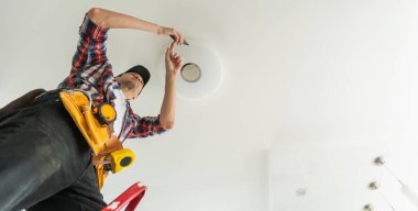 Müteahhit Elektrikçi. Lambayı tamir ediyorum. Yüksek kalite fotoğraf