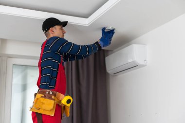 Bir elektrikçi tavana LED spot ışıkları kuruyor.