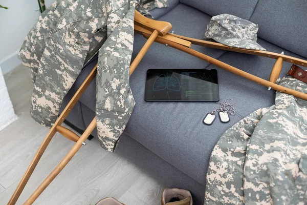military uniform with crutches and a tablet.