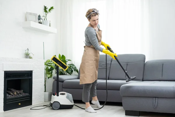 stock image Woman cleaning couch with vacuum cleaner at home.