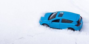 toy car rides on snow-covered highway in winter.