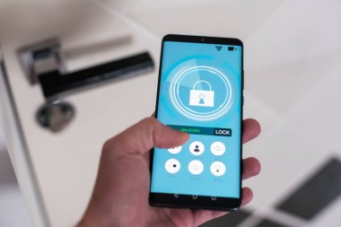 Akıllı ev, ev otomasyonu, uygulama simgeli aygıt. Adam akıllı telefonunu akıllı güvenlik uygulaması ile evinin kapısını açmak için kullanıyor. Yüksek kalite fotoğraf