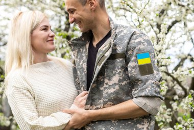 Savaştan sonra tanışan mutlu Ukraynalı çift. Üniformalı bir asker mutlu karısına sarılır..