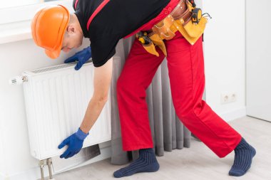 İş yerindeki tesisatçı. Su ısıtma radyatörü kuruluyor. Yüksek kalite fotoğraf
