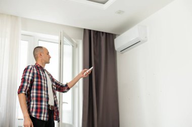 Uzaktan kumandalı klima tutan genç adam. Yüksek kalite fotoğraf