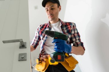 Marangoz kapı kilidini tamir ediyor. Kapı kolu takıyorum. Yüksek kalite fotoğraf