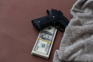 Nakit dolarların arka planında siyah silah. Para ya da para karşılığı cinayet kavramı. Banka soygunu. Yüksek kalite fotoğraf