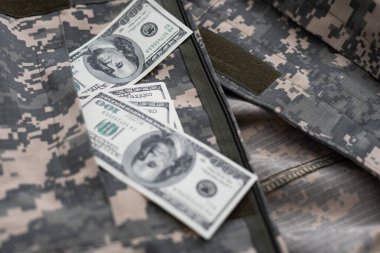 Ukrayna askeri kamuflajlı kumaş dokusuna Amerikan Doları banknotları. Gri, kahverengi ve yeşil pikselli kamuflaj desenli kumaş. Ukrayna askerlerinin resmi üniforması yaklaşıyor.