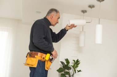 Elektrikçi tavan arasına lamba ışıklandırması ve spot çatı katı tarzı kuruyor.