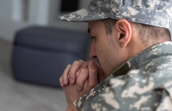 A man in a military uniform is sitting in a chair by the window. Concept: a soldier at a psychologists appointment, post-traumatic stress syndrome, mental disorder, the consequences of war.