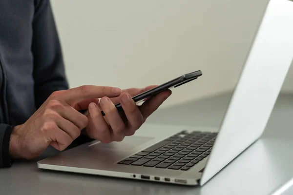 stock image Hand holding smartphone and using laptop