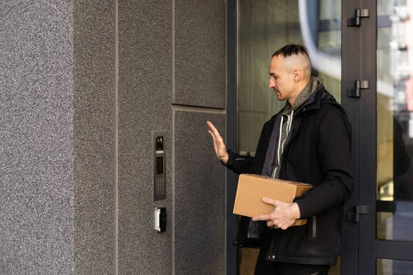 stock image Man ringing intercom with camera near building entrance