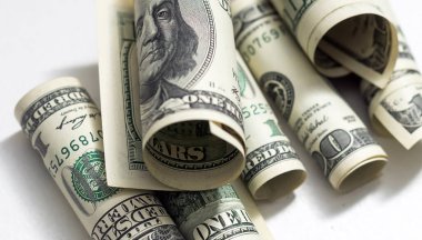 roles dollar notes in front of white background.