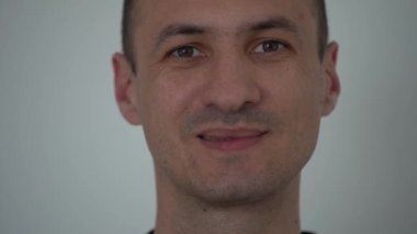 Beyaz arka planda sakin bir gülümsemeyle beyaz kostümlü beyaz yöneticinin yakın plan portresi kameraya yansıyor. Yüksek kalite 4k görüntü