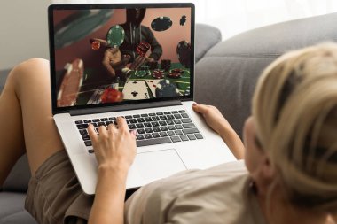 Telefonundaki kumar cep telefonu uygulamasını kullanarak bahis oynarken yakın plan çekimde çekilmiş. Bilgisayarından futbol maçı izleyip kazanmayı bekliyor. Yüksek kalite fotoğraf