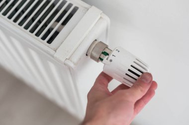 Isıtma maliyeti zammı nedeniyle enerji tasarrufu yapmak için radyatörün termostatını kapatmaya yakın çekim. Soğuk hava ve enerji krizinde maliyeti ekonomik hale getirme kavramı. Yüksek kalite fotoğraf