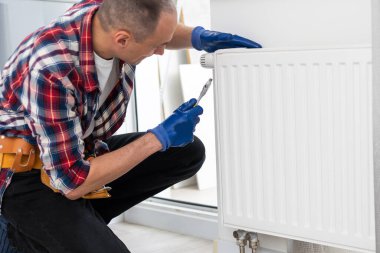 İş yerindeki tesisatçı. Su ısıtma radyatörü kuruluyor. Yüksek kalite fotoğraf