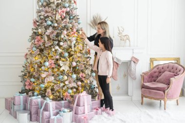 Anne ve kızı Noel ağacını birlikte süsler. Bir çocuk odasının şık bir iç mekanı. İskandinav eko-tarzı dekor. Yeni yıl kutlaması. Noel arifesi. Ortak zaman yönlendirmesini destekleyin. Aşk