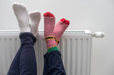 Anne ve kızın bacakları radyatörün yanında..