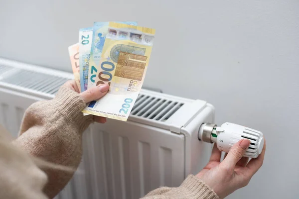 Γυναίκα Που Κρατάει Μετρητά Μπροστά Από Καλοριφέρ Θέρμανσης Πληρωμή Για — Φωτογραφία Αρχείου