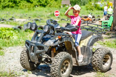 Bir çocuk çamurda dörtlü bisiklete biniyor. ATV binicisi.