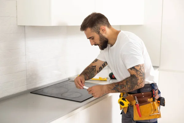 stock image craftsman installs hob in kitchen. Household Appliance Installation Services Concept.