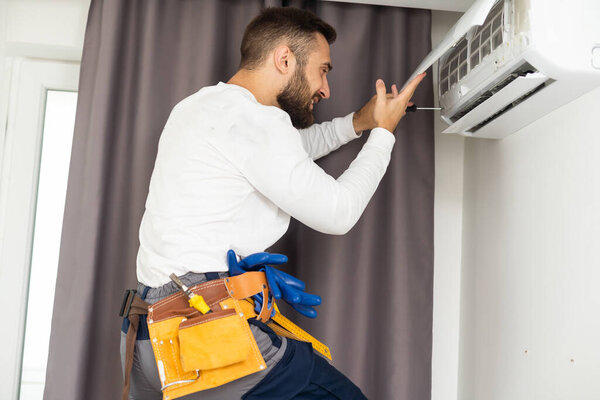 Техник по ремонту кондиционера на стене.