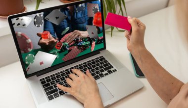 Telefonundaki kumar cep telefonu uygulamasını kullanarak bahis oynarken yakın plan çekimde çekilmiş. Bilgisayarından futbol maçı izleyip kazanmayı bekliyor. Yüksek kalite fotoğraf