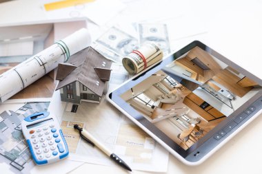 Architects workspace with tablet, small house model, drawing blueprints home renovation concept. High quality photo